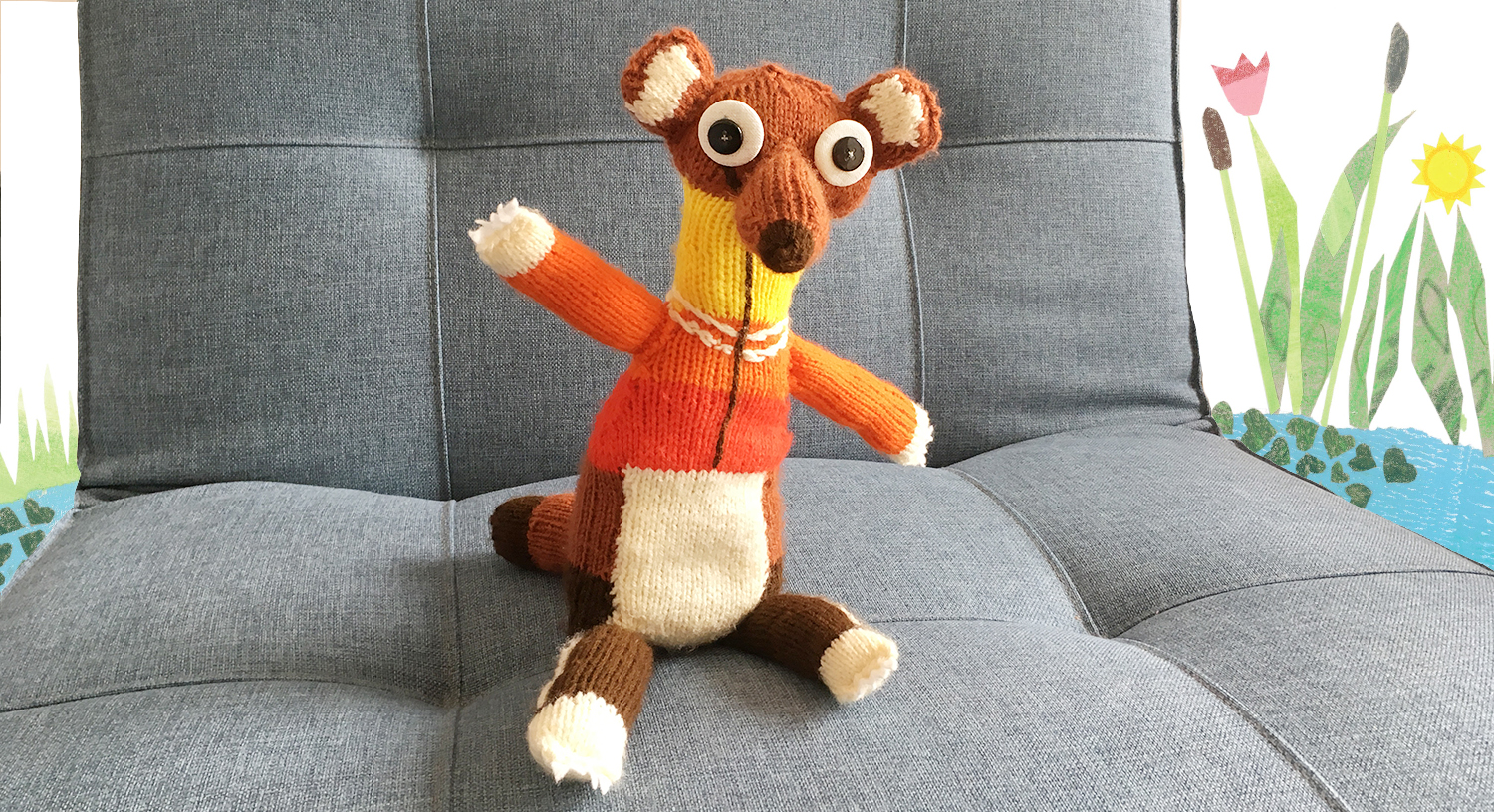 Gestrickter Ratzfatz sitzt am Sofa